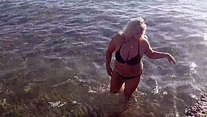 Milf plays with her big tits and ass on public beach