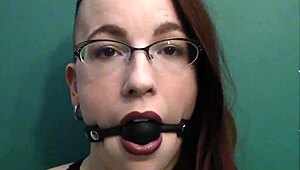 dark lipstick BALLGAG DROOLING with intense eye contact in close-up.