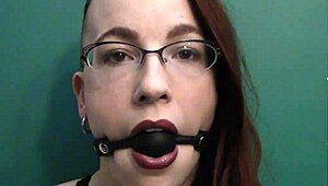 dark lipstick BALLGAG DROOLING with intense eye contact in close-up.