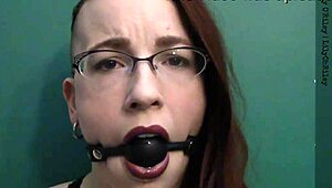 dark lipstick BALLGAG DROOLING with intense eye contact in close-up.