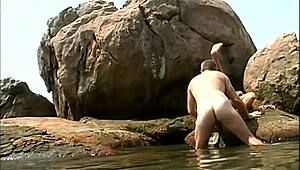 Does a mature man fuck an exotic babe on seaside stones?