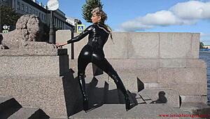latex mona in a sexy suit and high heels walks down the street